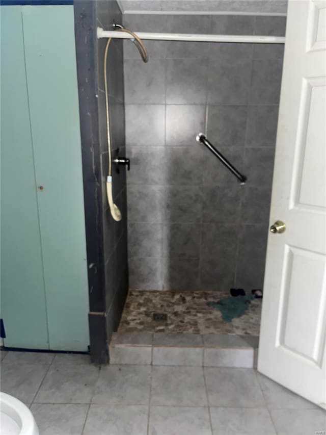 bathroom with a tile shower and tile patterned flooring