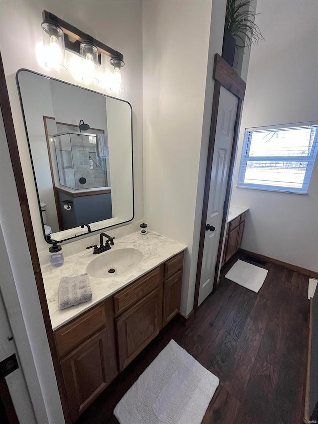 bathroom featuring wood-type flooring, toilet, vanity, and walk in shower