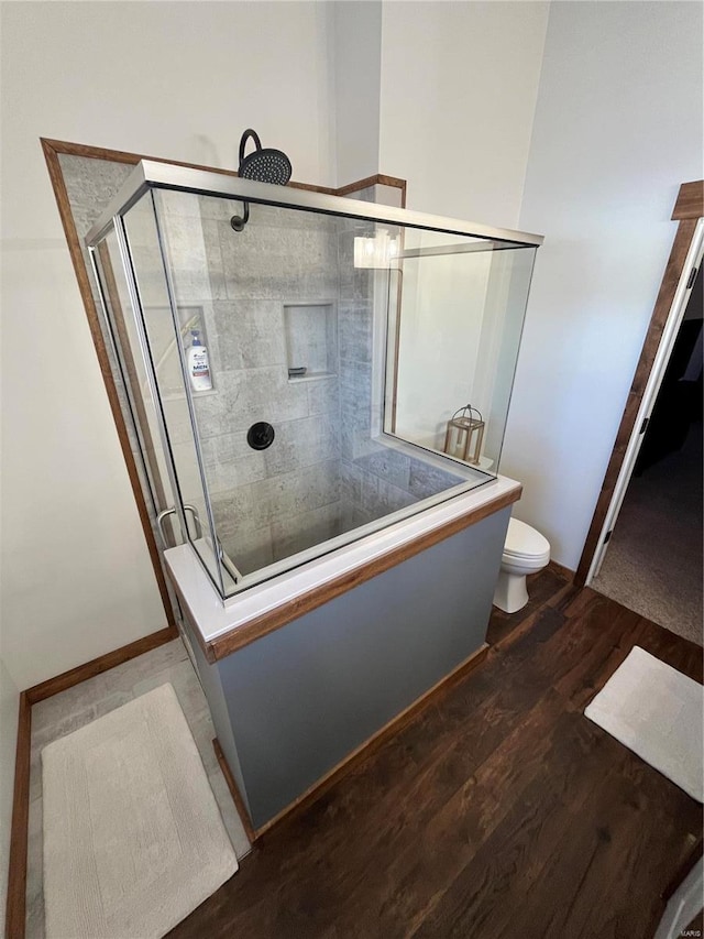 bathroom featuring walk in shower, toilet, and hardwood / wood-style floors