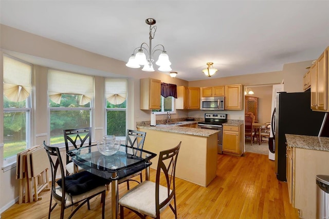 kitchen with stainless steel appliances, decorative light fixtures, kitchen peninsula, and light wood-type flooring