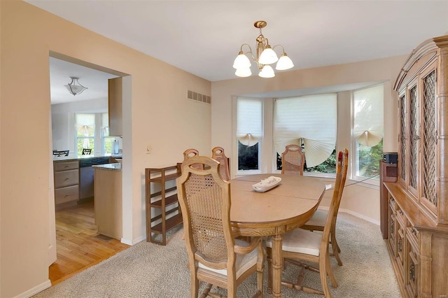 dining room with light carpet and a notable chandelier