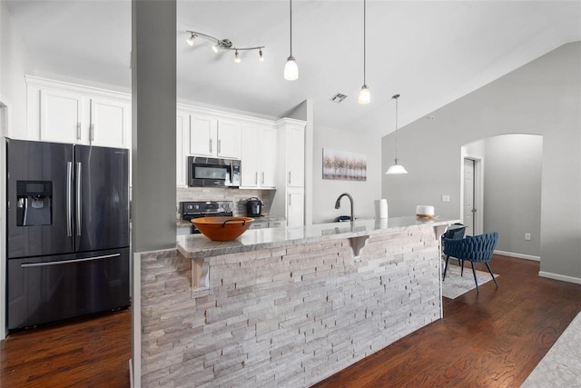 kitchen with a breakfast bar area, appliances with stainless steel finishes, white cabinetry, hanging light fixtures, and light stone counters