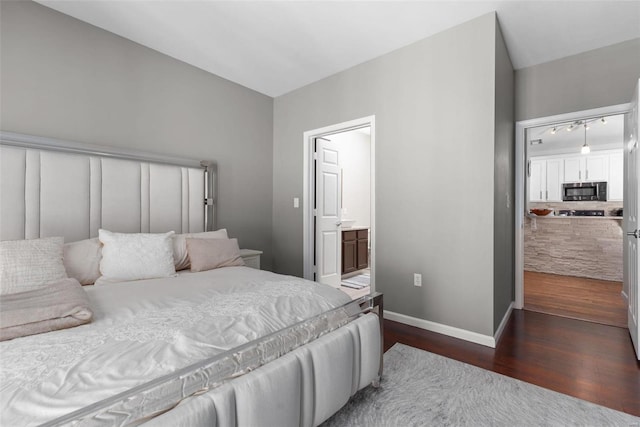 bedroom with ensuite bath and dark hardwood / wood-style flooring