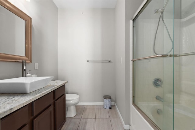 full bathroom with tile patterned flooring, vanity, bath / shower combo with glass door, and toilet