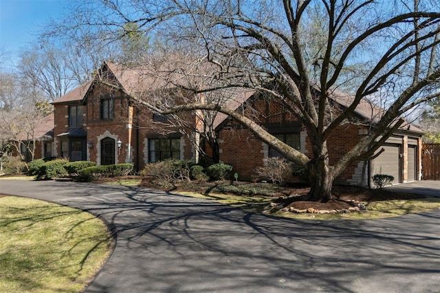 view of front of home with brick siding, an attached garage, and driveway