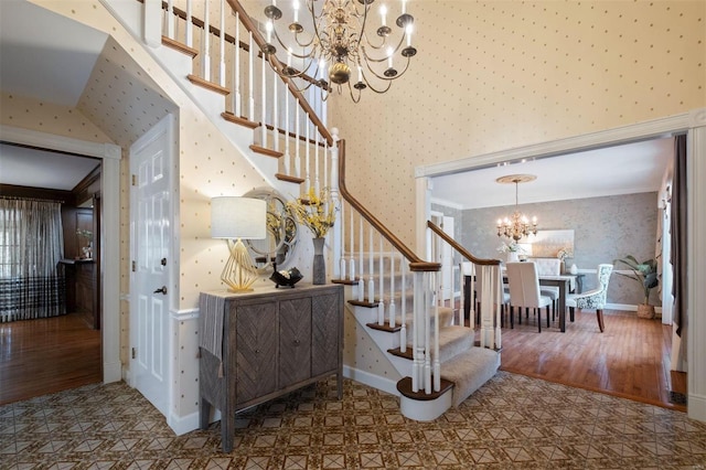 stairway featuring baseboards, a notable chandelier, wood finished floors, and wallpapered walls