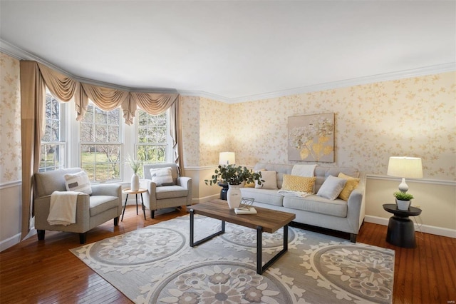 living room featuring baseboards, wood-type flooring, crown molding, and wallpapered walls