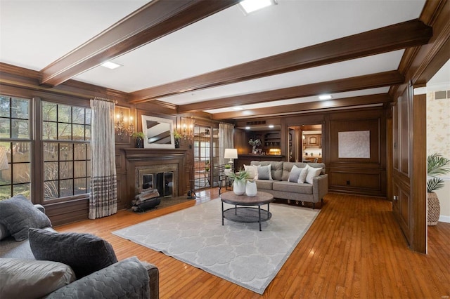 living room with a glass covered fireplace, hardwood / wood-style flooring, and beam ceiling