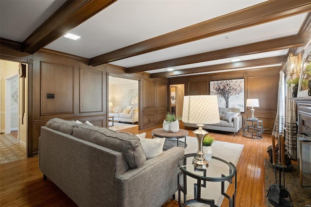 living area with light wood-type flooring, beam ceiling, a fireplace, and a decorative wall