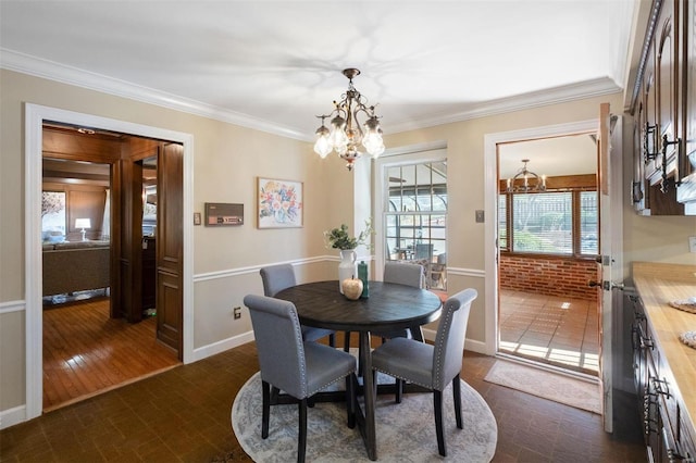 dining area with an inviting chandelier, baseboards, and ornamental molding