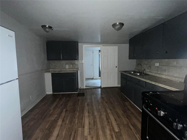 kitchen with dark hardwood / wood-style floors, tasteful backsplash, sink, white refrigerator, and black range