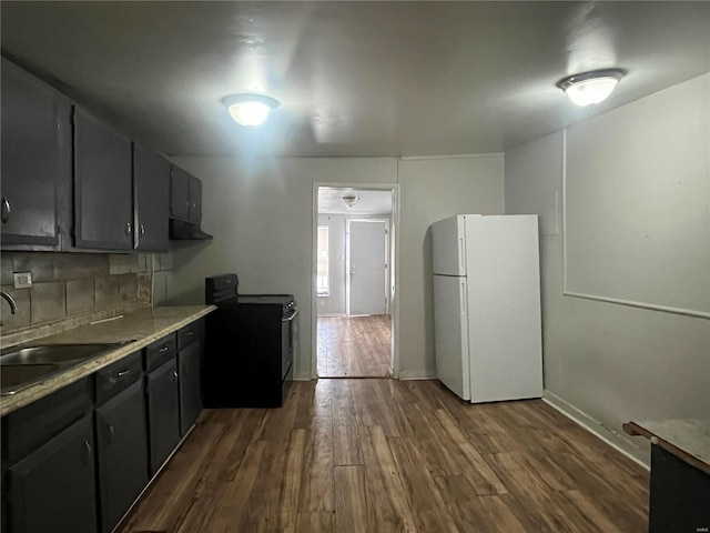 kitchen with white refrigerator, black / electric stove, dark wood-type flooring, and sink