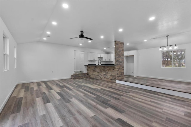 unfurnished living room with baseboards, ceiling fan, vaulted ceiling, a sink, and recessed lighting