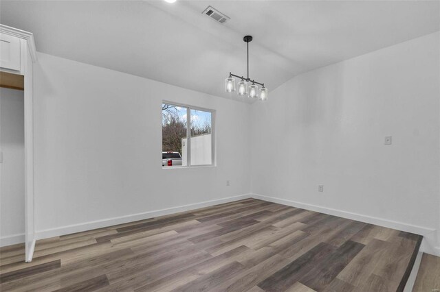 unfurnished dining area featuring lofted ceiling, wood finished floors, visible vents, and baseboards