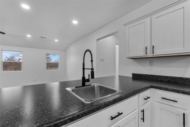 kitchen featuring dark countertops, white cabinets, a sink, and recessed lighting