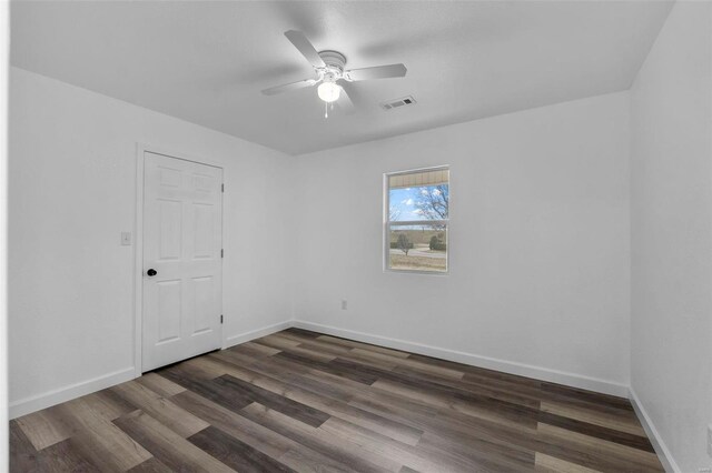 unfurnished room featuring visible vents, dark wood finished floors, baseboards, and ceiling fan