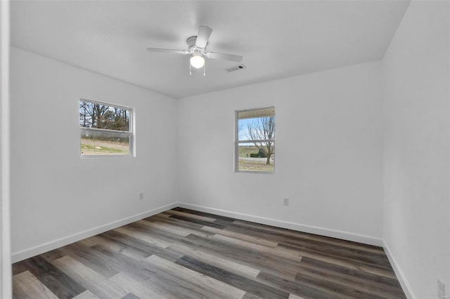 empty room featuring baseboards, plenty of natural light, visible vents, and wood finished floors