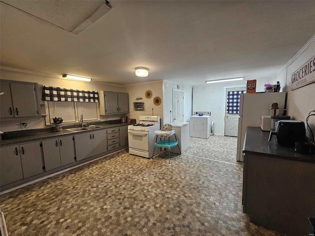 kitchen with separate washer and dryer, white range with gas cooktop, sink, and gray cabinetry