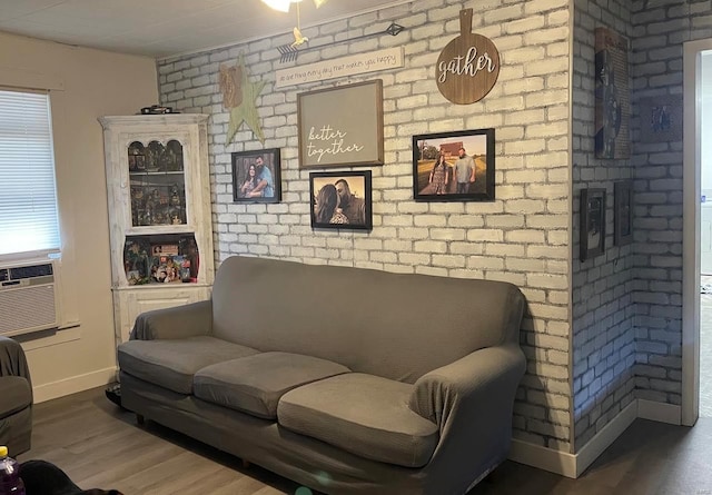 living room featuring hardwood / wood-style flooring and brick wall