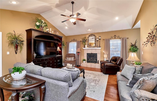 living room with vaulted ceiling, wood-type flooring, a healthy amount of sunlight, and a fireplace