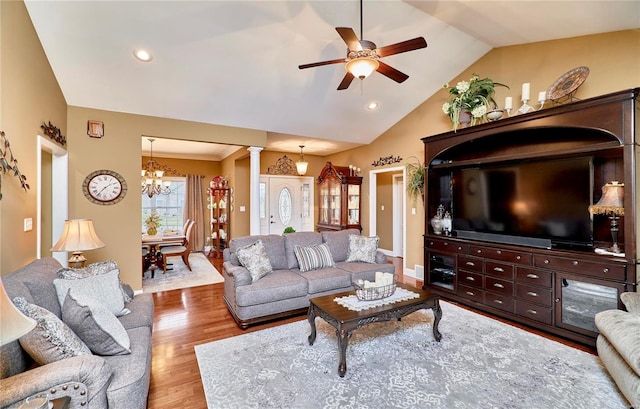 living room with hardwood / wood-style flooring, vaulted ceiling, ornate columns, and ceiling fan with notable chandelier