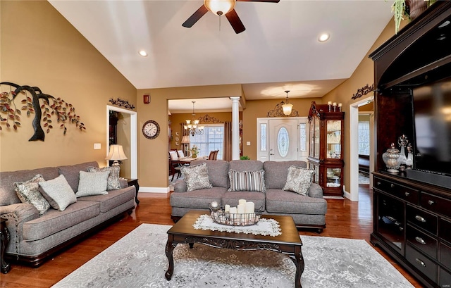 living room with lofted ceiling, dark hardwood / wood-style floors, ceiling fan with notable chandelier, and ornate columns