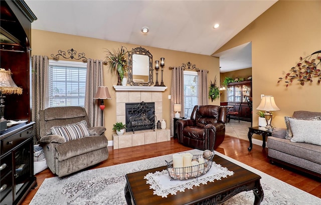 living room featuring a wealth of natural light, a tile fireplace, dark hardwood / wood-style floors, and vaulted ceiling