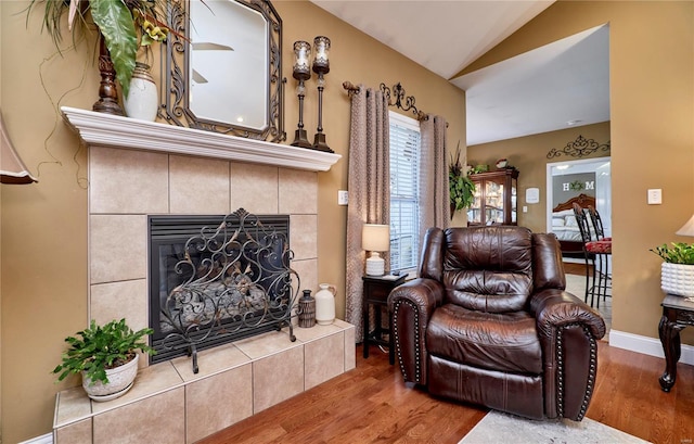 living area featuring lofted ceiling, a fireplace, and wood-type flooring