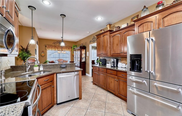 kitchen with appliances with stainless steel finishes, decorative light fixtures, tasteful backsplash, sink, and dark stone countertops