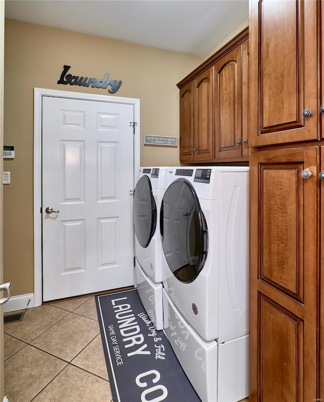 washroom featuring cabinets, washing machine and clothes dryer, and light tile patterned floors