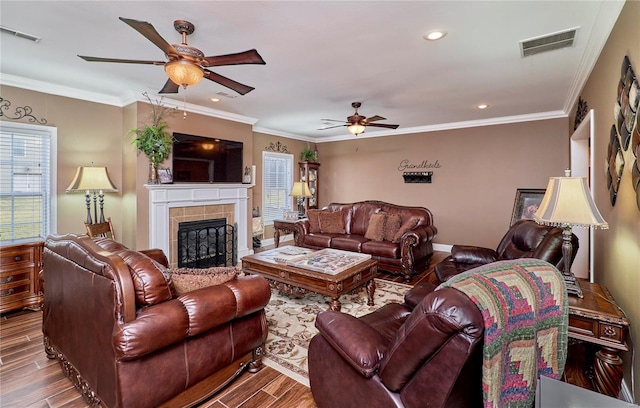 living room with ceiling fan, ornamental molding, and a tile fireplace