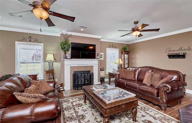 living room with ceiling fan, ornamental molding, a fireplace, and light wood-type flooring