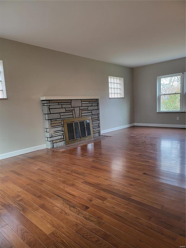 unfurnished living room with a fireplace, wood finished floors, and baseboards