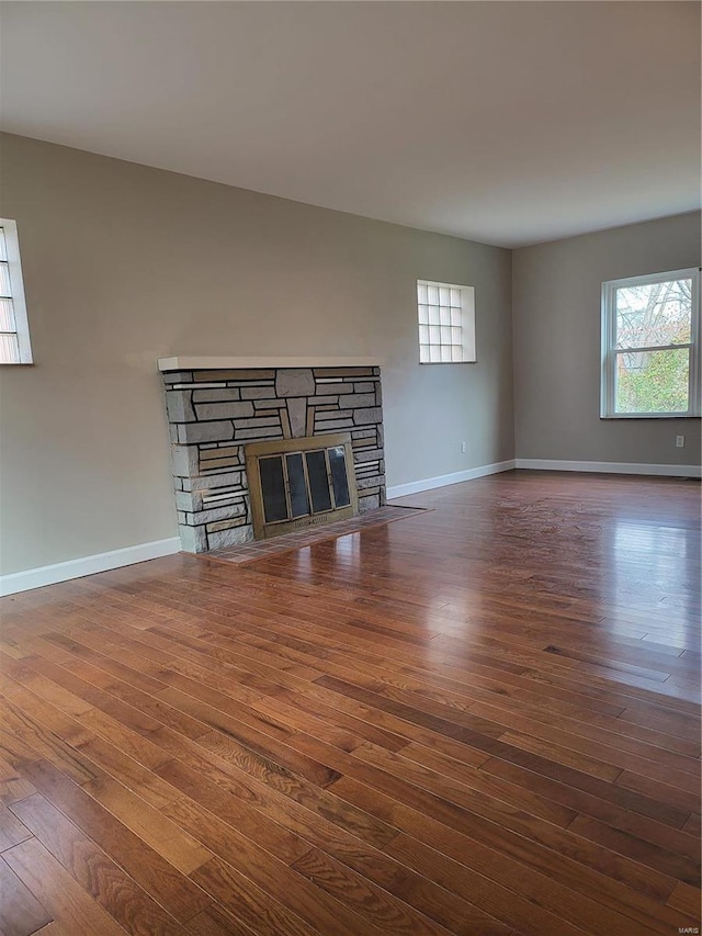 unfurnished living room with a fireplace, wood finished floors, and baseboards