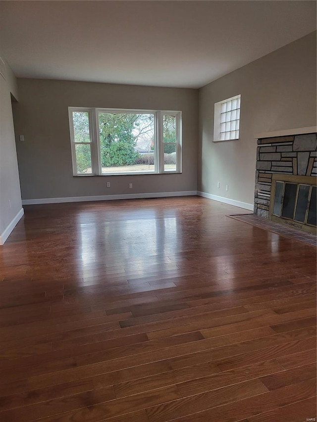 unfurnished living room with a fireplace, baseboards, and wood finished floors