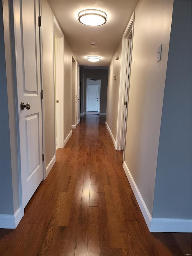 hallway with dark wood-style flooring and baseboards