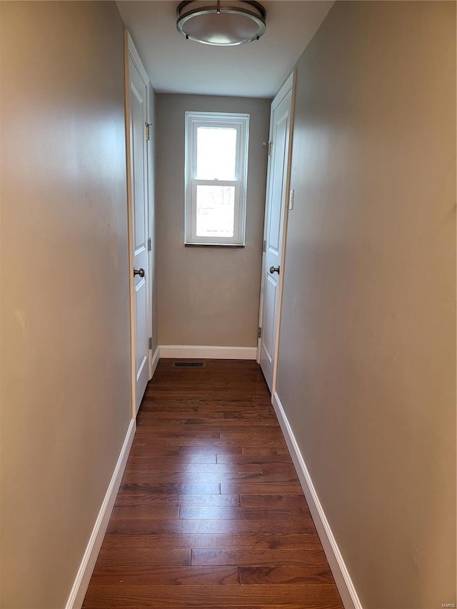 corridor featuring dark wood-type flooring, visible vents, and baseboards