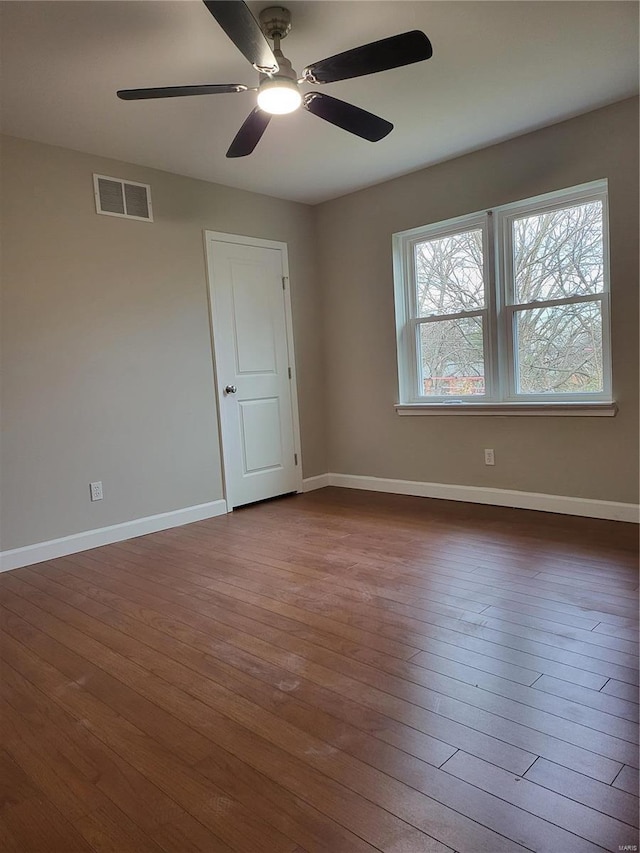 unfurnished room with dark wood-type flooring, visible vents, and baseboards