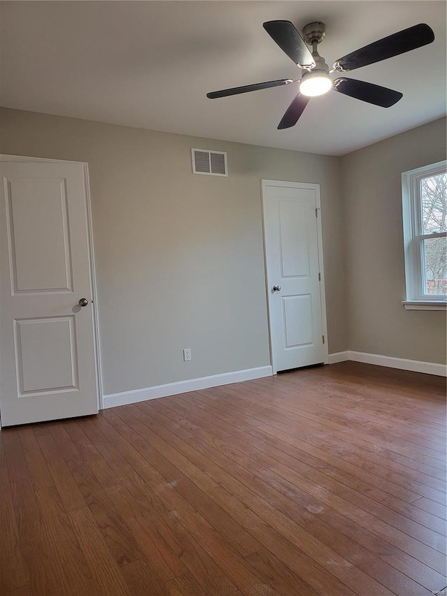 spare room featuring dark wood-style flooring, visible vents, and baseboards