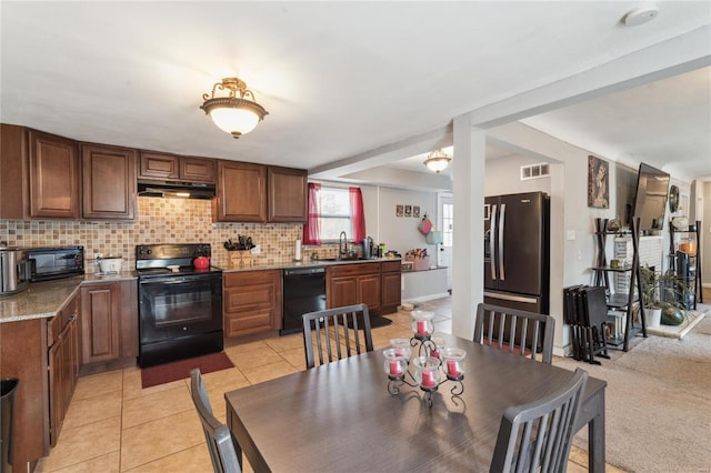 kitchen featuring sink, light tile patterned floors, backsplash, light stone counters, and black appliances