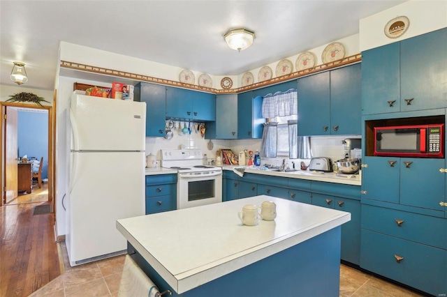 kitchen with sink, white appliances, a center island, and blue cabinets