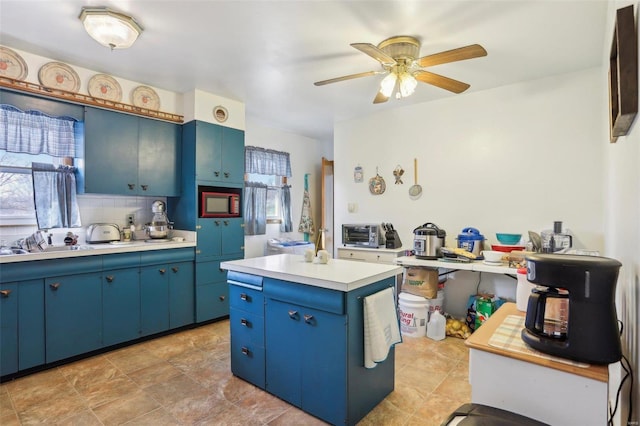 kitchen with blue cabinetry, sink, a kitchen island, ceiling fan, and backsplash