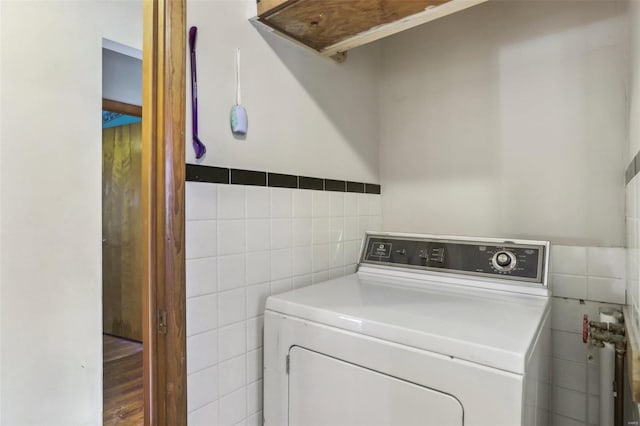 washroom with hardwood / wood-style flooring, washer / dryer, and tile walls