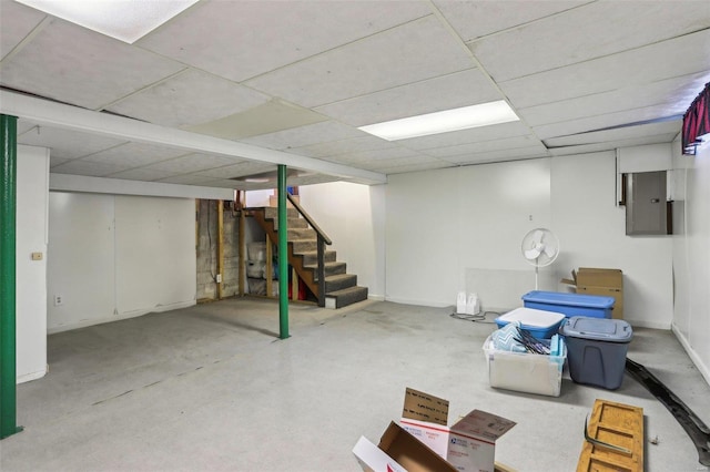 basement featuring a drop ceiling and electric panel