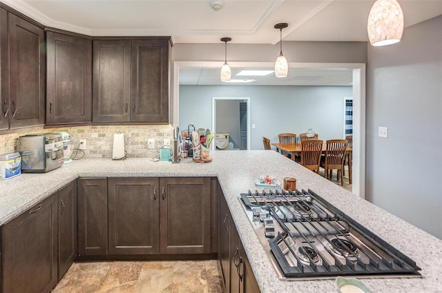 kitchen featuring backsplash, dark brown cabinetry, light stone counters, decorative light fixtures, and stainless steel gas stovetop