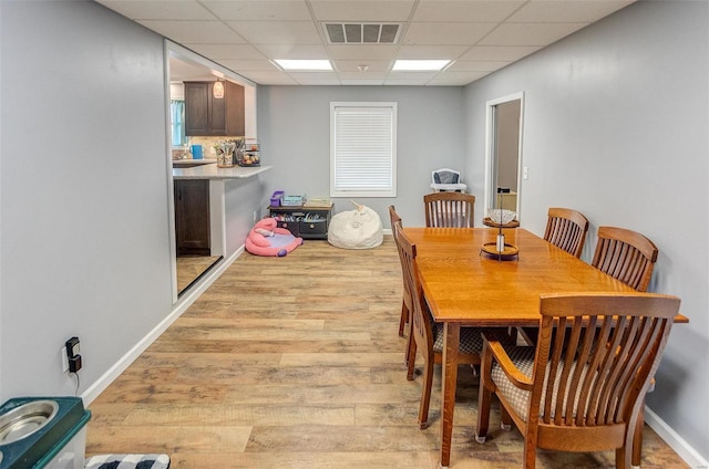 dining room featuring light hardwood / wood-style flooring and a paneled ceiling