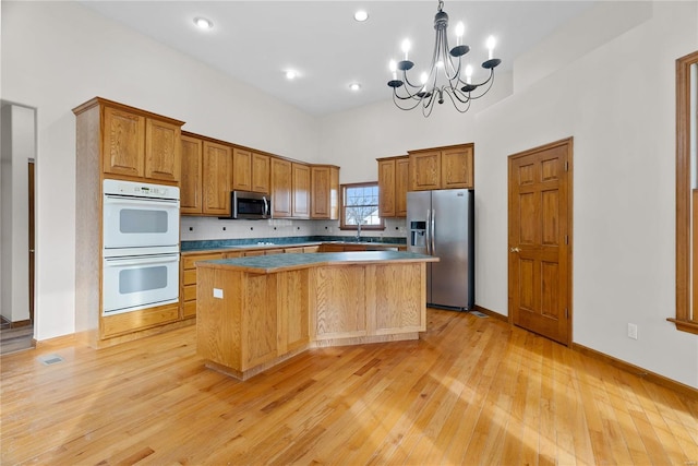 kitchen featuring stainless steel appliances, a kitchen island, light hardwood / wood-style floors, decorative backsplash, and pendant lighting