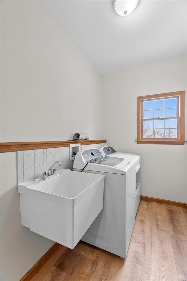 laundry area with washer and dryer, sink, and light hardwood / wood-style flooring