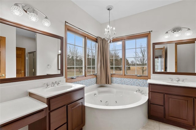 bathroom featuring a notable chandelier, vanity, tile patterned flooring, and a bathing tub