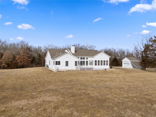 rear view of property featuring a garage, a yard, and an outdoor structure